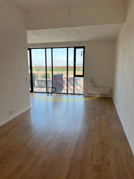 Living room of a two-room apartment with a wooden decor floor and large windows.