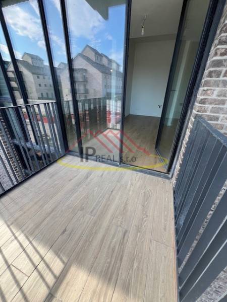 A balcony with a wooden decor floor in a 2-room apartment, overlooking buildings.