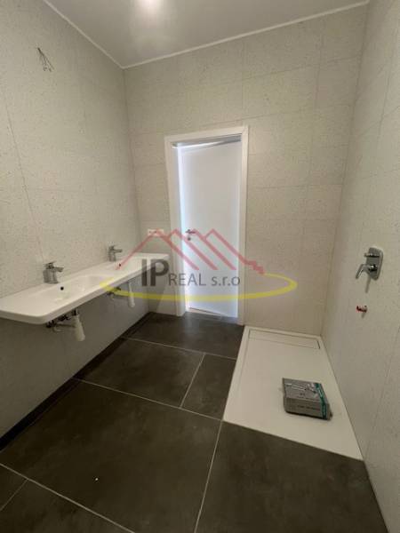 A bathroom with a large sink and a shower tray in a 2-room apartment.