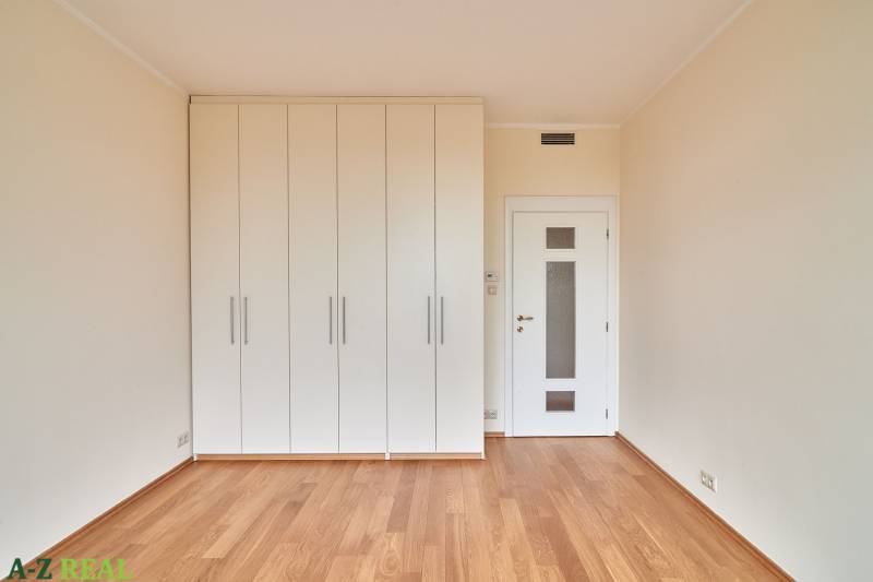 A bright room with wood-patterned flooring and white built-in wardrobes in a 3-room apartment.