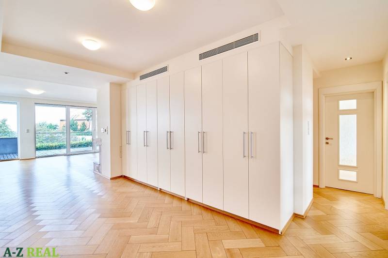 Interior of a 3-room apartment with white storage cabinets and a wooden decor floor.