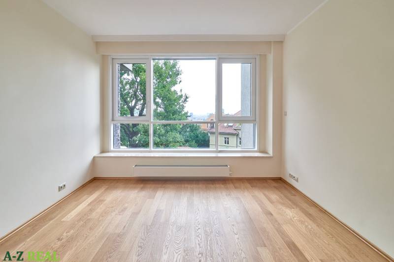 A room with a large window and a wooden decor floor in a 3-room apartment.