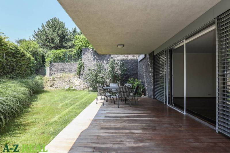 A terrace with a wooden decor floor, garden seating, and greenery by a 3-room apartment.