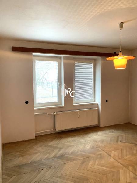 A room with a light wood-patterned floor, a radiator, and lighting in a 2-room apartment.