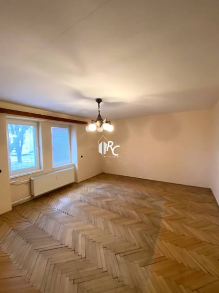 A room in a 2-room apartment with a wooden decor floor and a central chandelier.