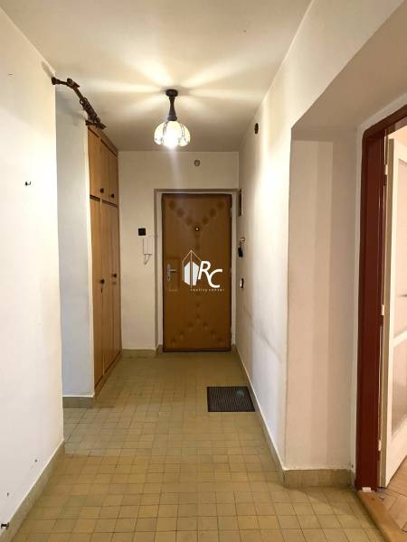 A hallway in a 2-room apartment with tiles and built-in wardrobes.