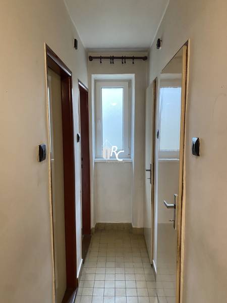 A narrow hallway in a 2-room apartment with light-colored flooring.