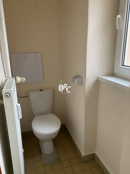Toilet with radiator and window in a 2-room apartment.