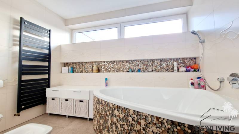 Bathroom with a bathtub and mosaic tiles in a family house.