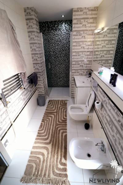 Bathroom with a sink, bidet, and shower in a family house. Walls with mosaic.