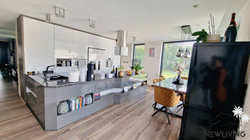 A kitchen in a family house with a wooden decor floor, a dining table, plenty of light.