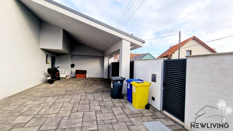 A family house on Jánošíkova Street with a spacious yard, a garage, and waste bins.