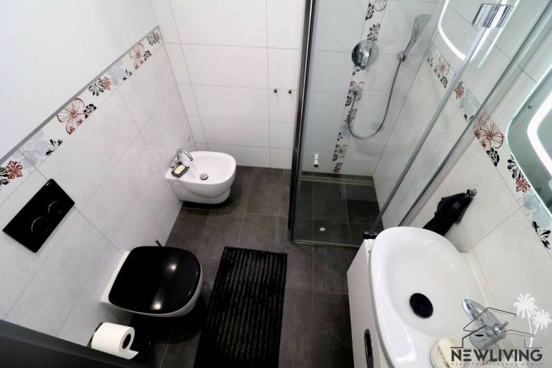 A bathroom in a family house with colorful tiles, a shower corner, and a sink.