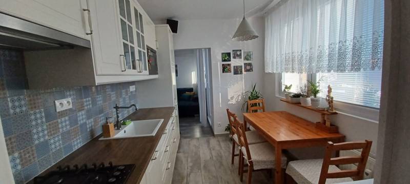 A kitchen in a 3-room apartment with a wooden decor, a dining table, and plants.