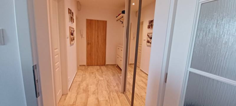 A hallway in a 3-room apartment with a wooden decor floor and a built-in wardrobe.