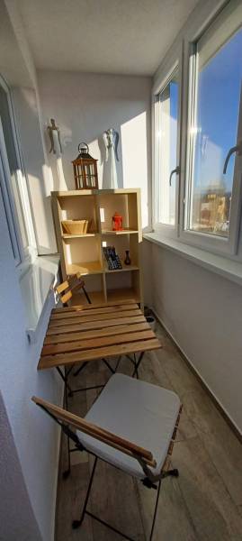 Balcony of a 3-room apartment with furniture and a wooden table, floor with wooden decor.