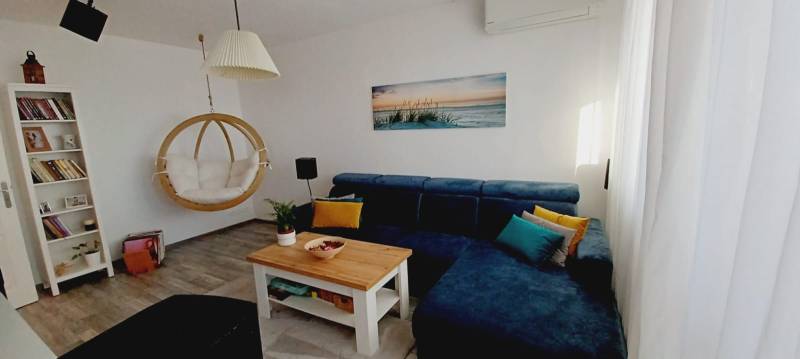 Living room with a blue sofa, swing, bookshelf, and floor with a wood decor.