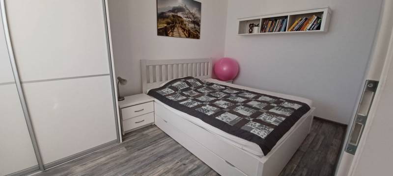Bedroom in a 3-room apartment with a wardrobe, bed, books, and a floor with wood decor.