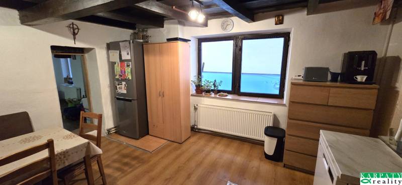 A kitchen in a family house with a wood-patterned floor, a table, and a refrigerator.