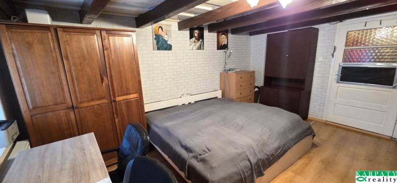 A bedroom in a family house with a wooden beam ceiling, furniture, and decorative paintings.
