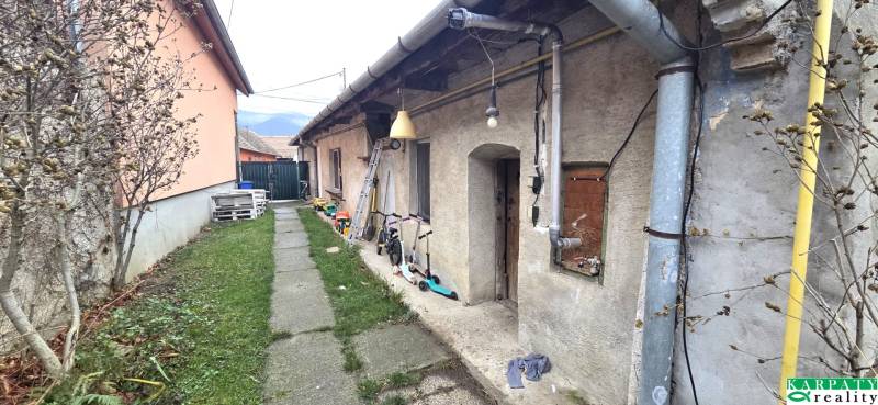 Exterior of a family house in Dolné Orešany with a walkway, children's toys, and greenery.