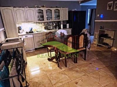 A kitchen in a family house with ceramic tiles, wooden cabinets, and a dining table.