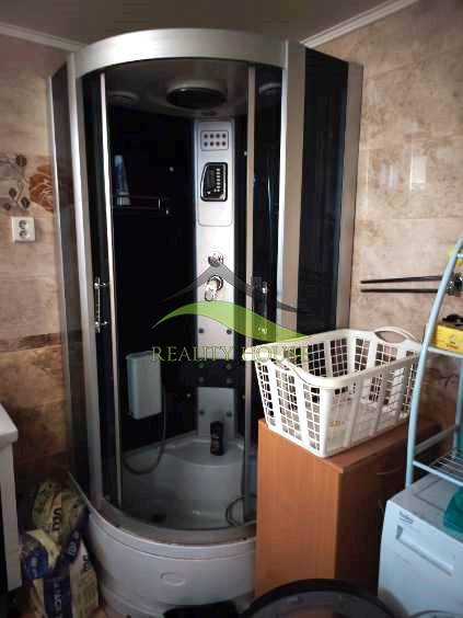 Bathroom in a family house with a massage shower cabin and a laundry basket.