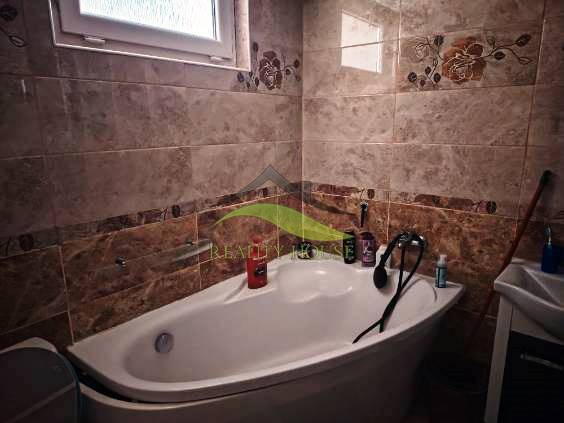 Bathroom in a family house with a bathtub and a tiled wall.