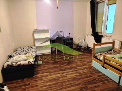 Interior of a family house with beds and wood-patterned flooring.