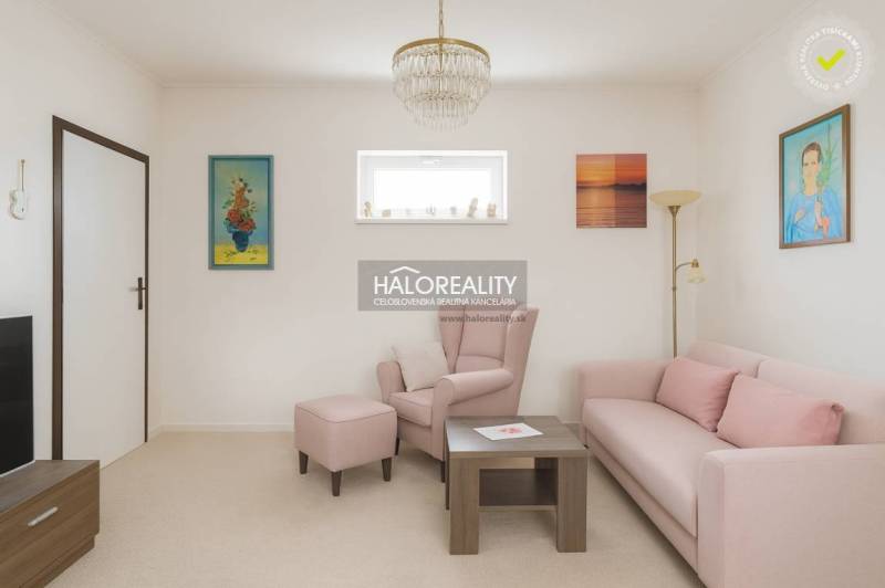 Living room with a pastel sofa and armchair in a family house, decorative paintings on the walls.