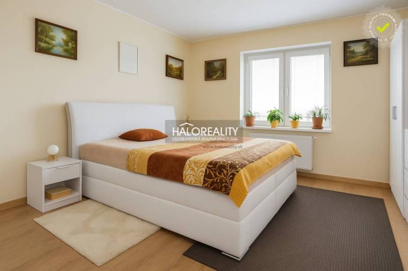 Bedroom in a family house with a bed, nightstand, and a window with houseplants.