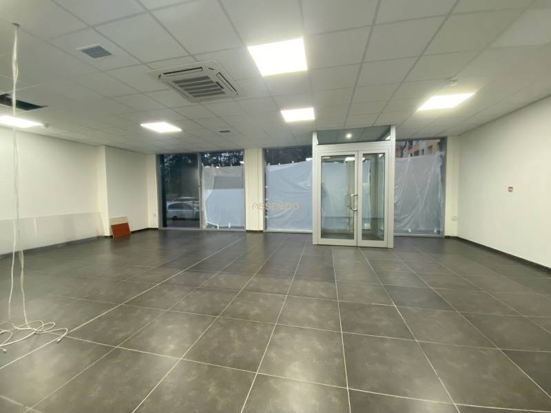 Commercial premises with dark tiles, glass doors, and a suspended ceiling.