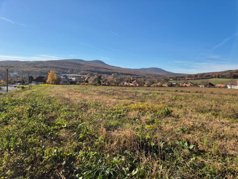 View of the plots - housing in Velčice with hilly landscape in the background.