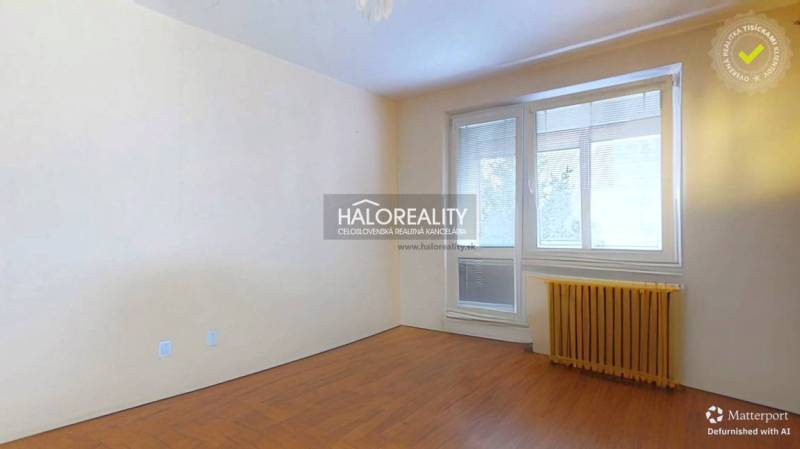 A room with a wooden decor floor in a 3-room apartment, a bright space with blinds.