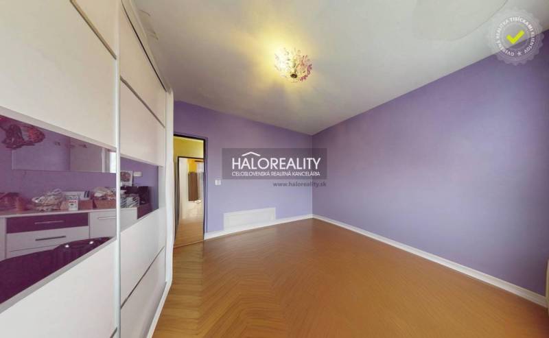 Purple room with wood-patterned flooring in a three-room apartment.