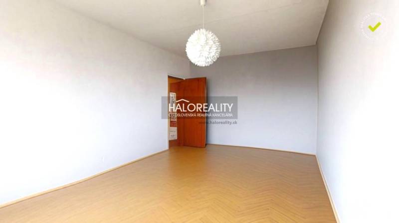 The room in the three-room apartment has a wooden decor floor and a white wall.