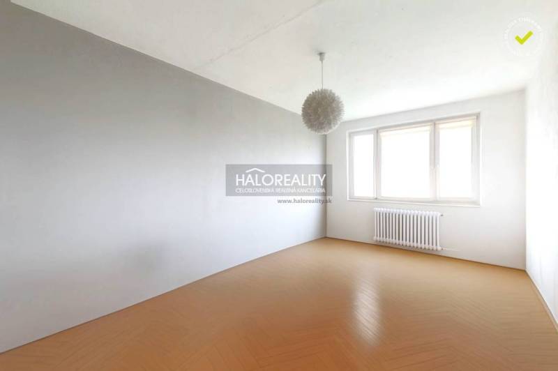 A bright room in a 3-room apartment with a wooden decor floor and a large window.