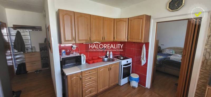 A kitchen in a studio apartment with wooden cabinets, a microwave, and a stove.