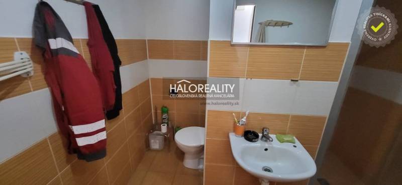 Bathroom with toilet and sink in a studio apartment with tiles in warm tones.