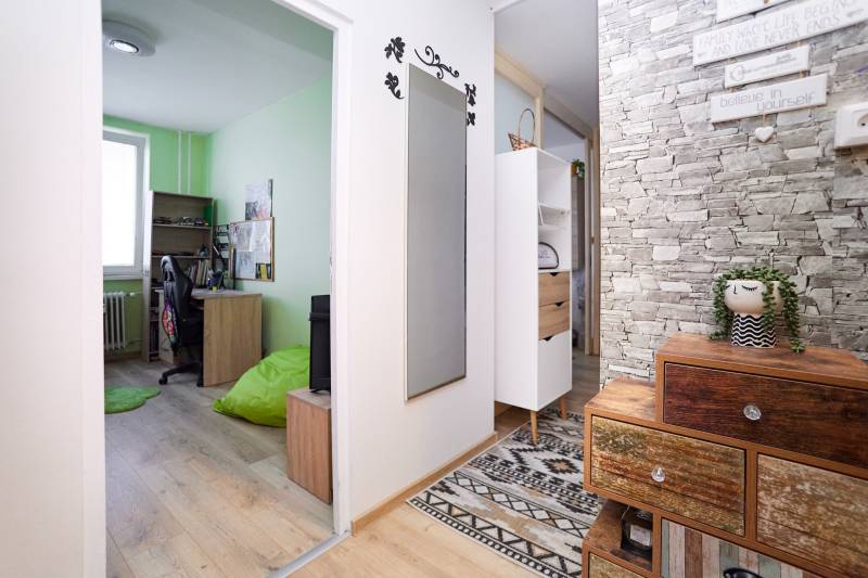 A hallway with colorful furniture, a green wall, and a wooden decor floor in a 2-room apartment.