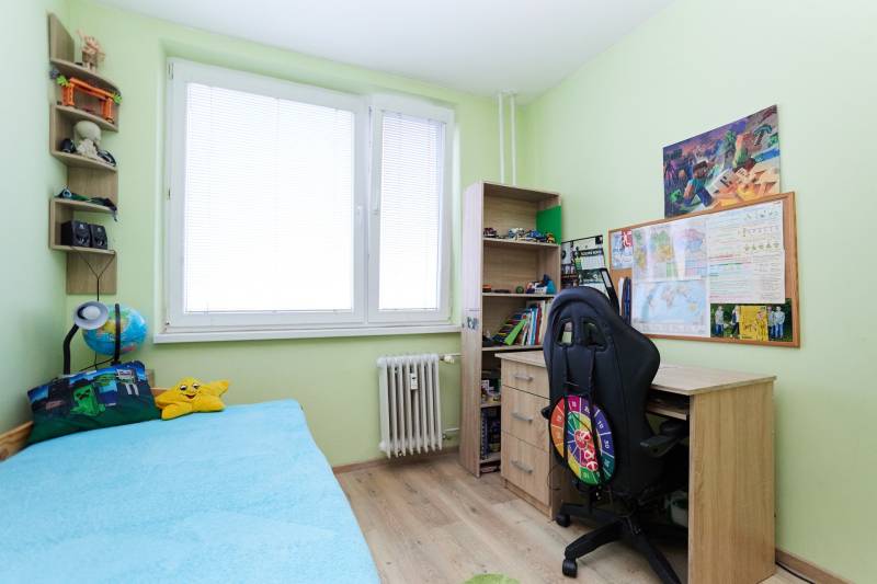 Children's room in a two-room apartment with a bed, desk, and floor with a wooden decor.