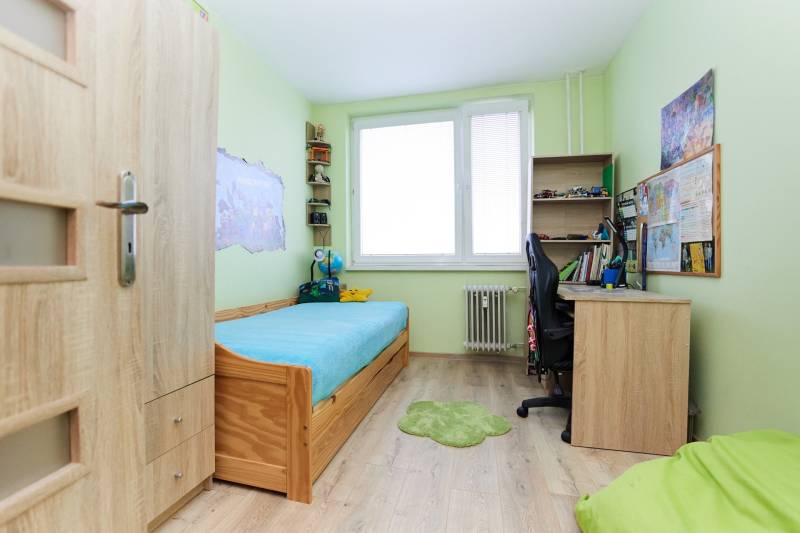 Children's room with a bed, a desk, and a floor with a wooden decor in a two-room apartment.