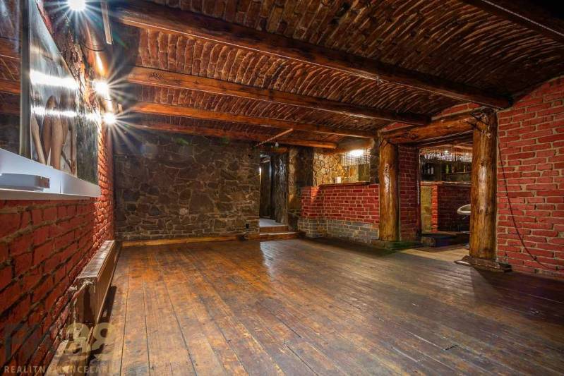 Interior with wood-patterned flooring, brick and stone walls, ceiling with wooden beams.