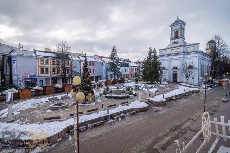 Square with a church and a Christmas tree in Poprad, snow-covered buildings, urban architecture.