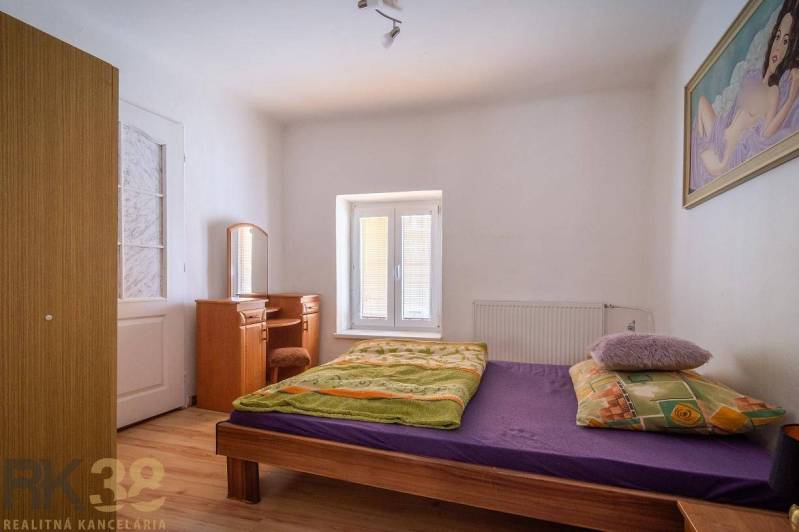 Bedroom with a bed, mirror, and wooden decor flooring.