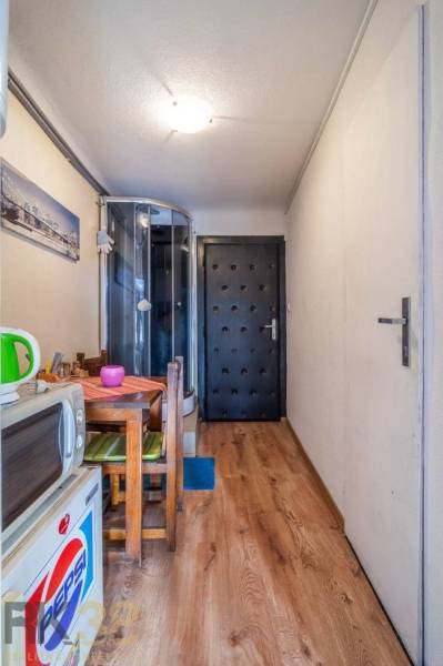 A narrow space with a kitchen table and a shower corner. Floor with wood decor.