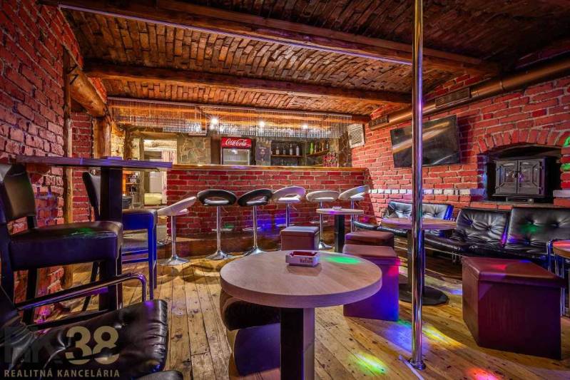The interior of a bar with wood-patterned flooring, red bricks, and a bar counter.