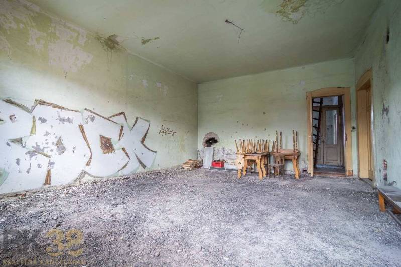 An abandoned room with graffiti on the walls, chairs piled on the table. The building needs renovation.