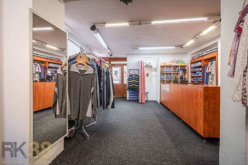A clothing store with a carpet, a wooden counter, and a large mirror.