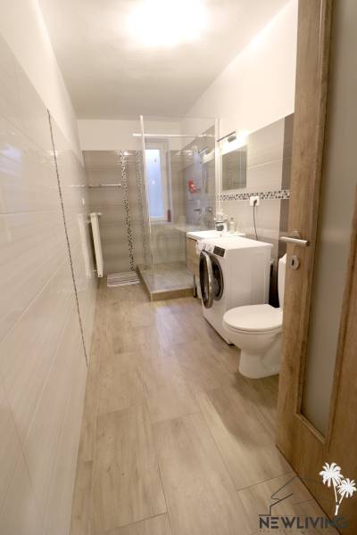 A bathroom in a family house with tiled walls and a wooden decor floor.